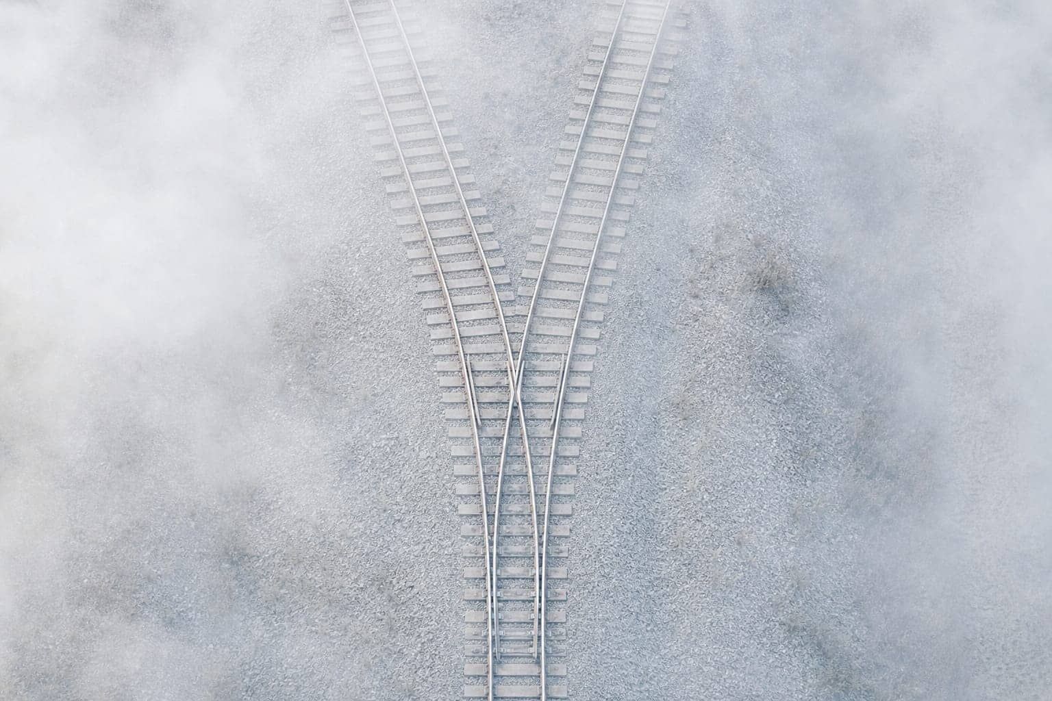 Vía de tren que se divide en dos, vista desde arriba entre la niebla